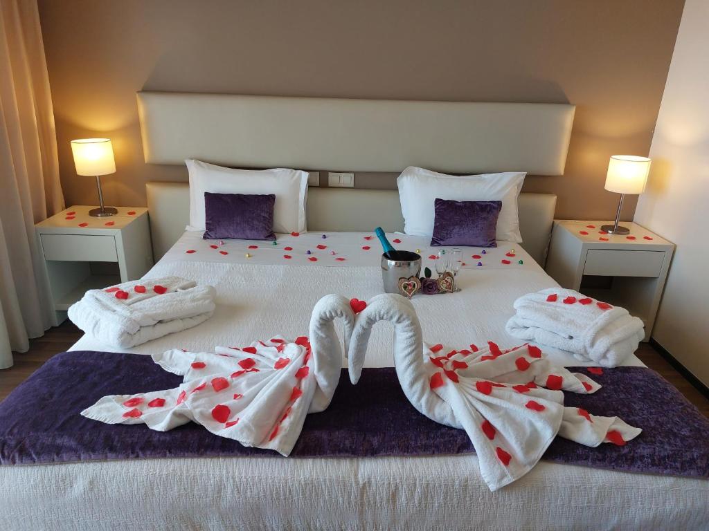 a bedroom with a bed with two towels and two lamps at Hotel Monte Lírio in Espinho