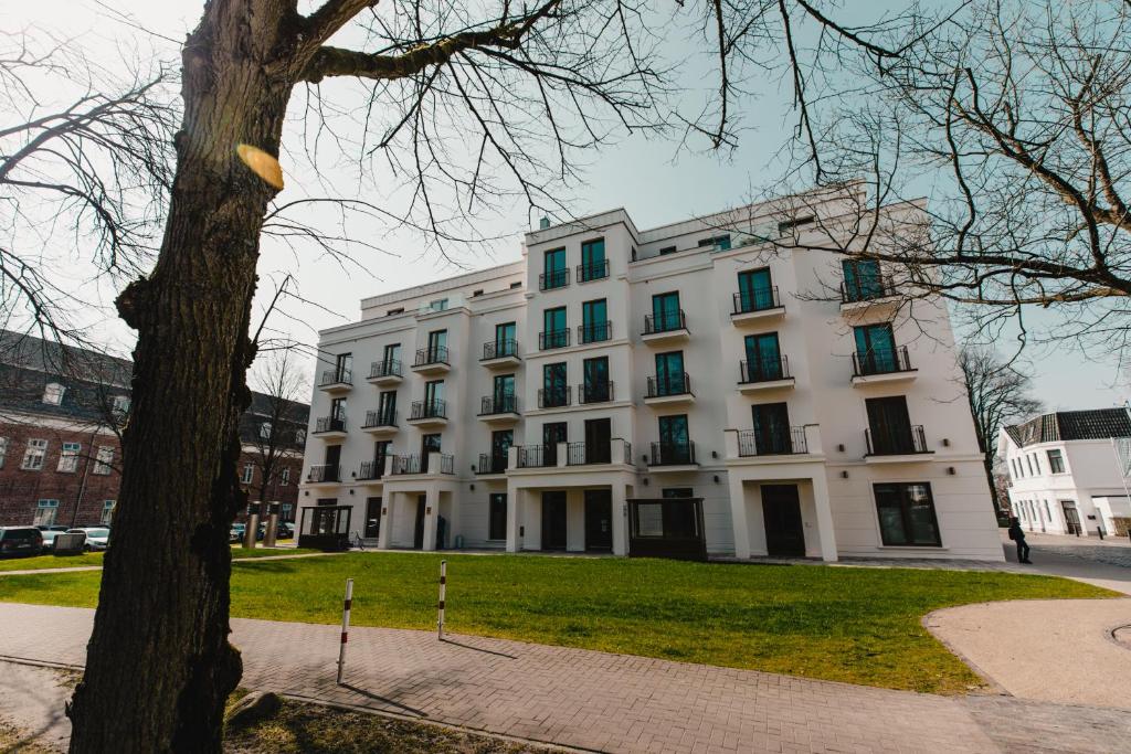 un edificio blanco con un árbol delante en Hotel Am Schloss Aurich - Schlossresidenz, en Aurich