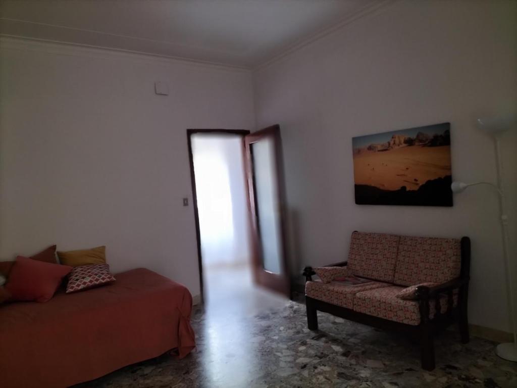 uma sala de estar com um sofá e uma cadeira em Casa del Grillo in centro e nei pressi del mare em Catânia