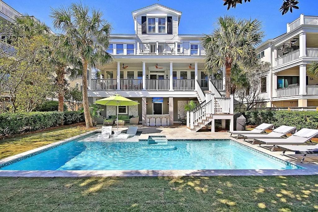 a large house with a swimming pool in front of a house at Luxury Modern Home- Steps 2 Beach, Private Pool/Bar, Sleeps 16, 7 BD-5.5 BR- 'The Lucky Penny' in Isle of Palms