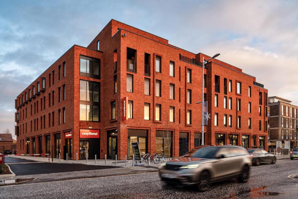 a car driving past a brick building on a street at easyHotel Oxford in Oxford