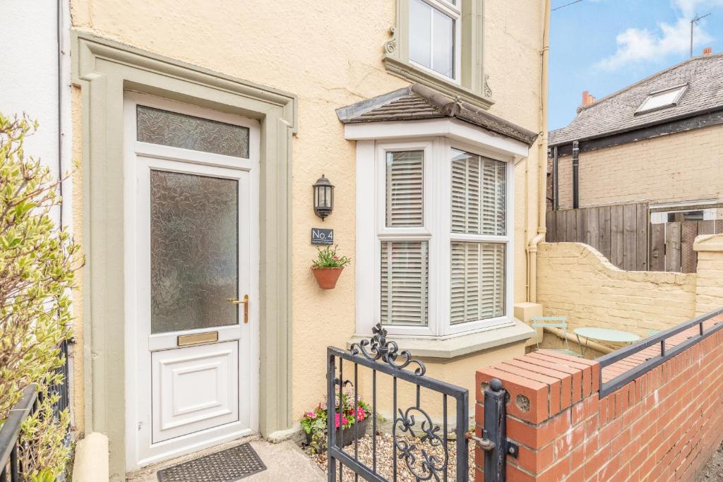 a house with a white door and a fence at Postman's Cottage in Bridlington