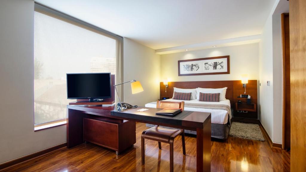 1 dormitorio con 1 cama y escritorio con TV en Select Elegant Apartments by Time Hotel & Apartments, en Santiago