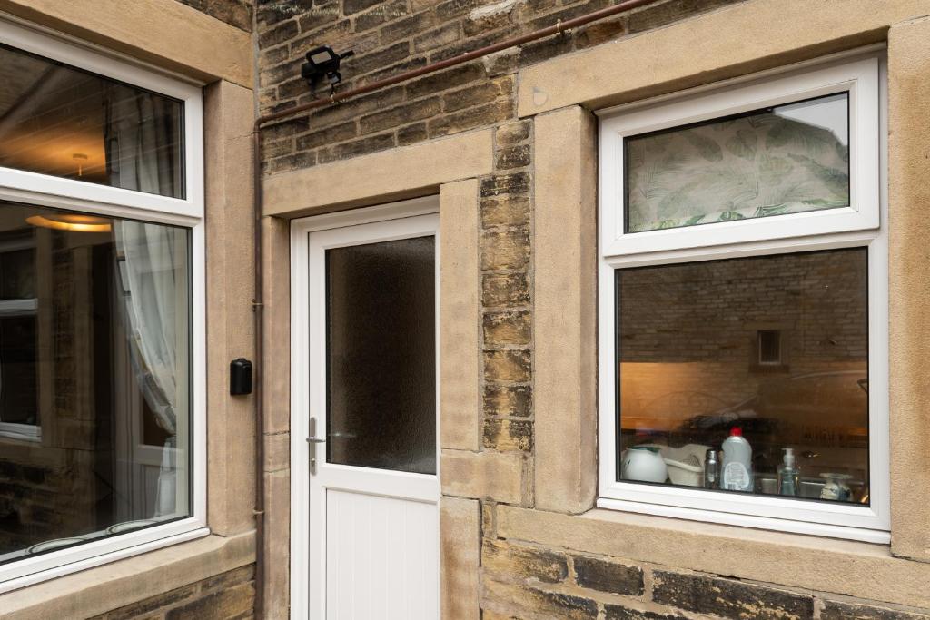 a brick building with two windows and a white door at CRAVEN VUE - SKIPTON in Skipton