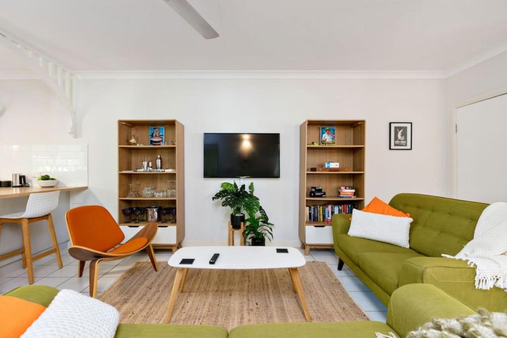 uma sala de estar com um sofá verde e uma mesa em Tiki Dreams - With A Large Breezy Balcony em Westcourt