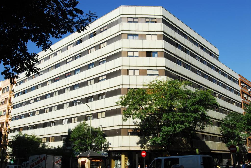 un edificio blanco alto con un árbol delante de él en Apartamentos Goya 75, en Madrid