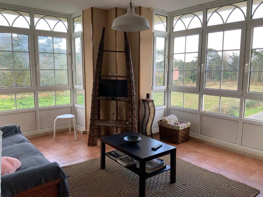 een woonkamer met ramen, een bank en een tafel bij Finis Viae in Fisterra