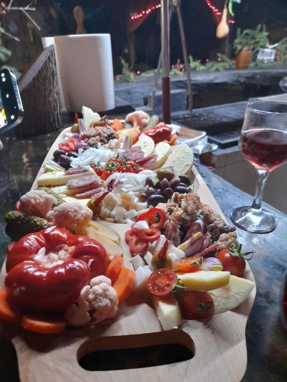 un mucchio di cibo su un tagliere con un bicchiere di vino di Monte grego a Slava Rusă