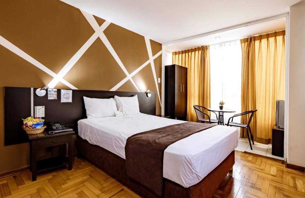 una habitación de hotel con una cama grande y una mesa en El Centurión, en Trujillo