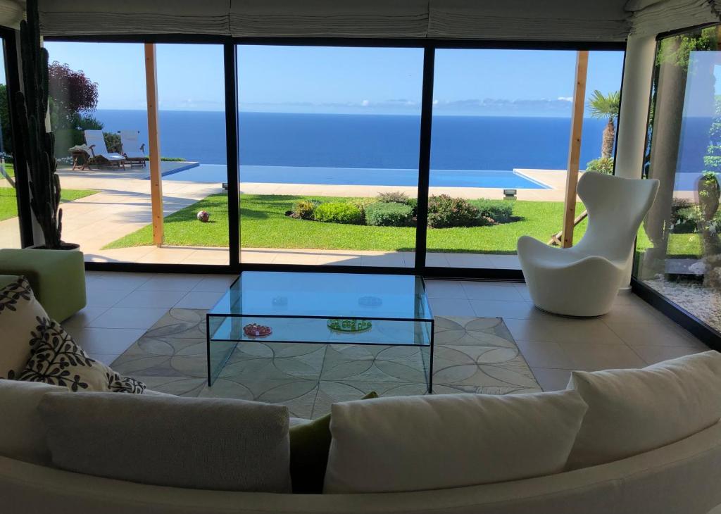 a living room with a white couch and a glass table at Morning Star Villa in Arco da Calheta