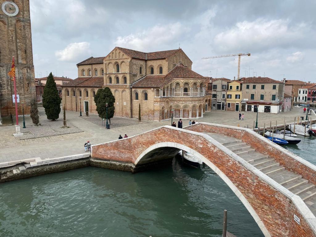 DUOMO Murano Apartment with Canal view في مورانو: جسر فوق نهر امام مبنى