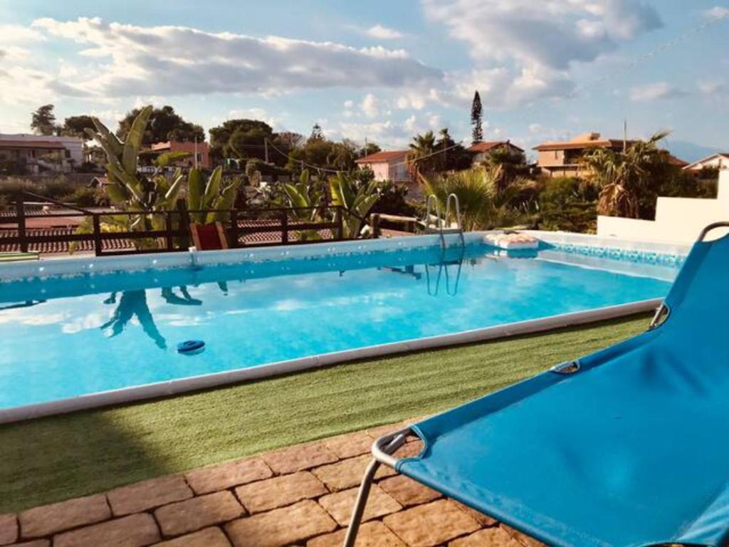 uma piscina azul com uma cadeira ao lado em Al Meriggio Apartments em Brucoli