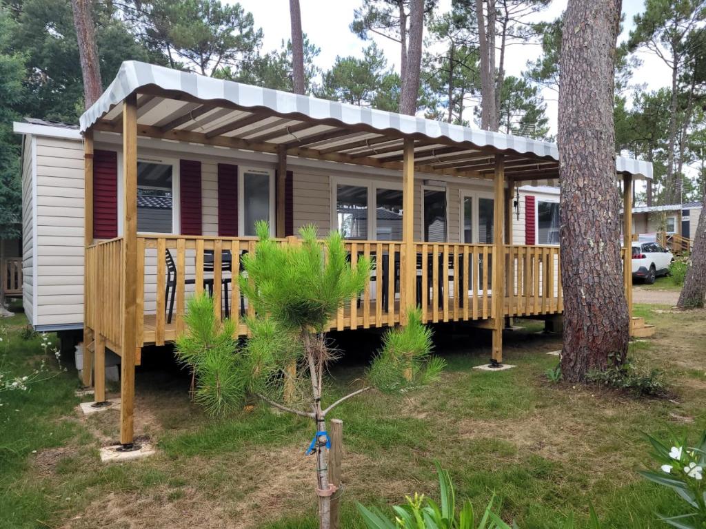 een hut in het bos met een houten terras bij mobil home - camping les dunes de Contis in Saint-Julien-en-Born