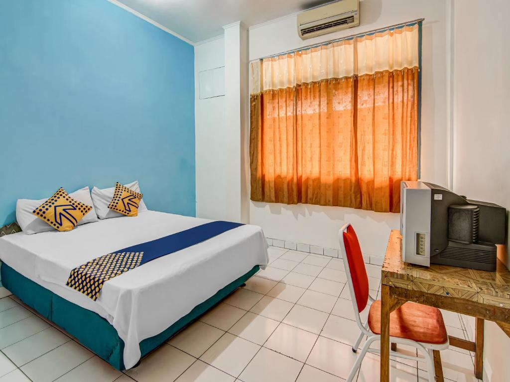 Schlafzimmer mit einem Bett, einem Schreibtisch und einem TV in der Unterkunft SPOT ON 90964 Hotel Margadana in Tegal