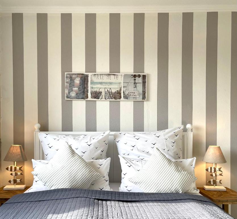 格洛米茨的住宿－Moin Grömitz，一间卧室设有条纹墙和一张带白色枕头的床