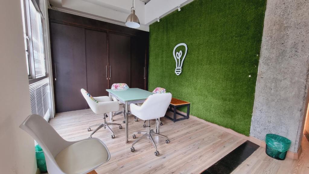 una mesa y sillas en una habitación con una pared verde en Habitat Suites Hotel, en Pereira