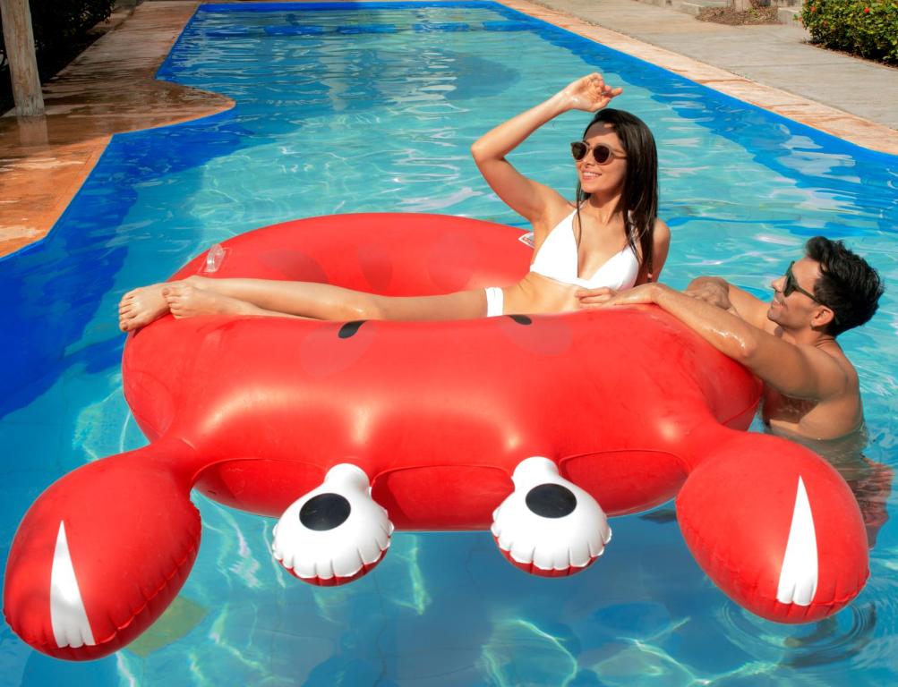 un hombre y una mujer tumbados sobre un oso inflable en una piscina en Paraíso Seyba Hotel, en Seybaplaya