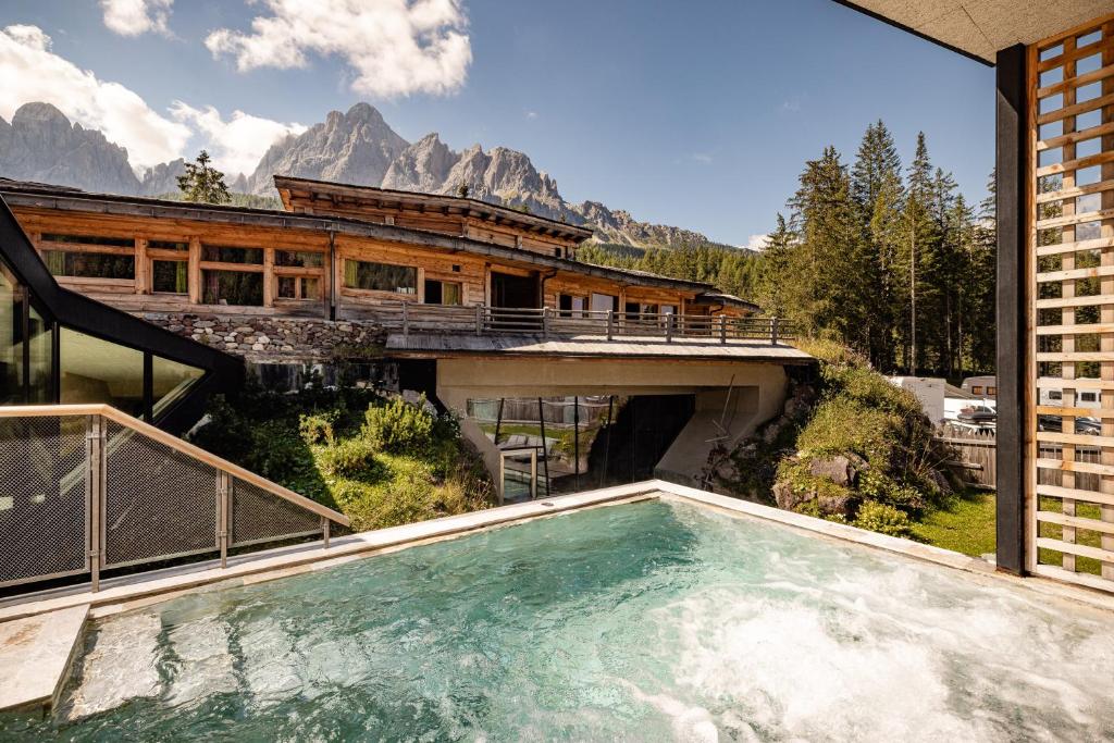 a house with a swimming pool in front of a mountain at Mountain Resort Patzenfeld in Sesto