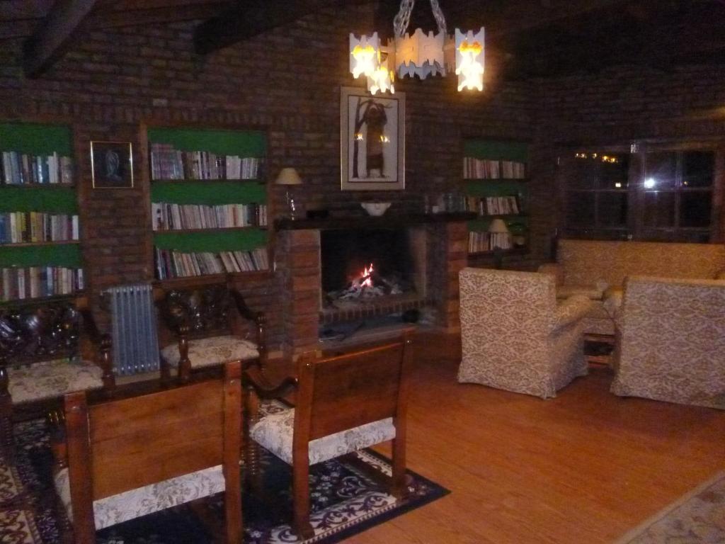 a living room with a fireplace and book shelves with books at Hosteria Pastoral & Spa in La Cumbre