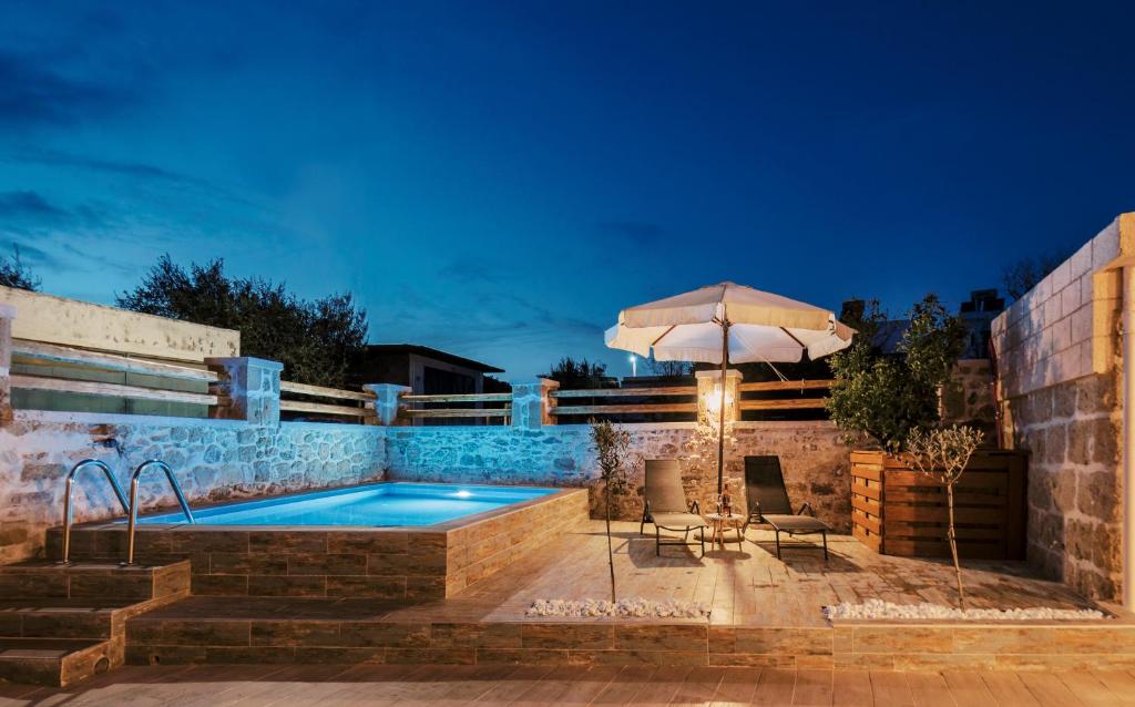 a pool with two chairs and an umbrella at Villa Gemma in Haraki