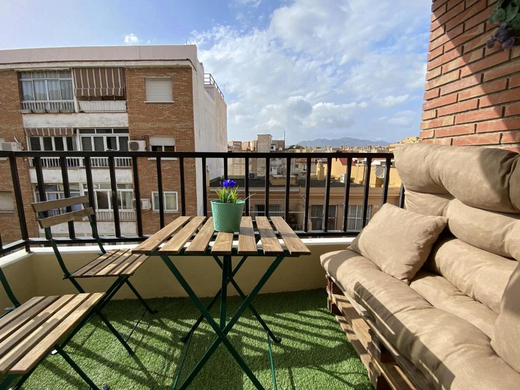 un patio con divano e tavolo sul balcone. di Balcón Victoria a Málaga