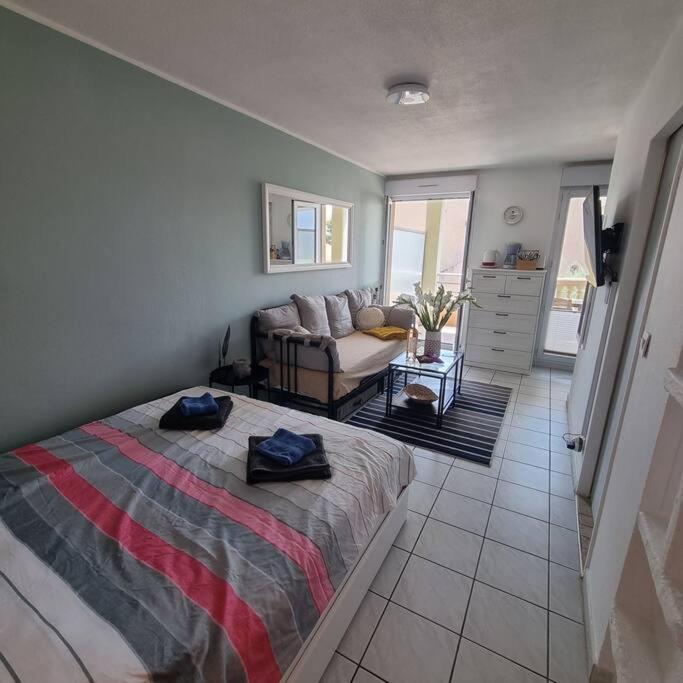 une chambre avec un lit et un salon avec un canapé dans l'établissement Gemütliches Studio, Pool, Parkplatz. Ohne Vis-a-vis., à Fréjus
