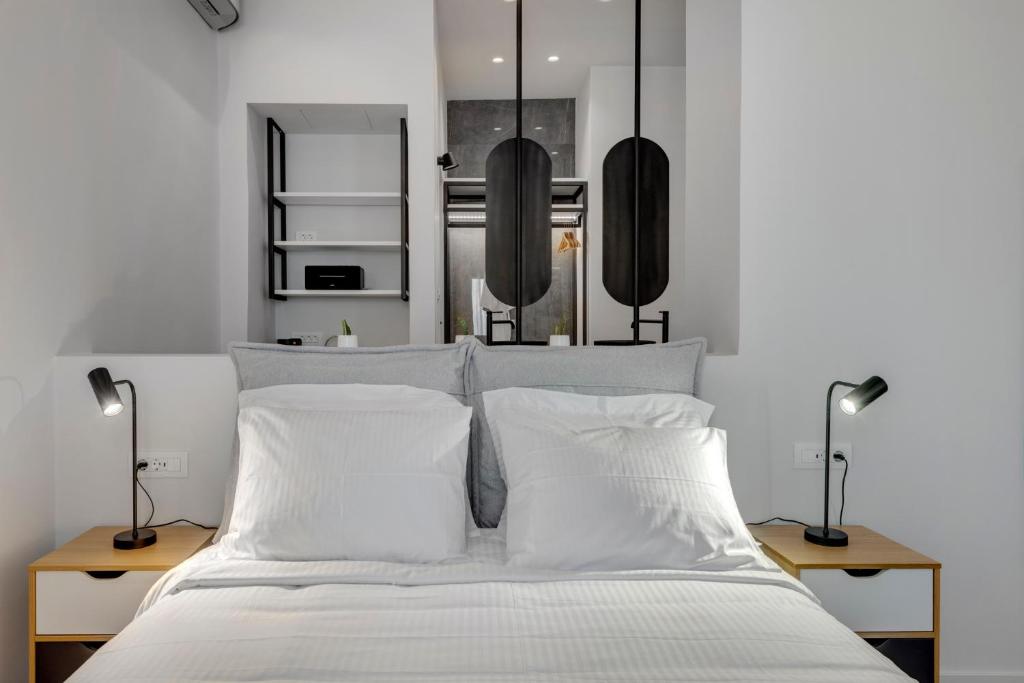 ein Schlafzimmer mit einem weißen Bett mit zwei Lampen in der Unterkunft Times Elegant Rooms in Ermoupoli