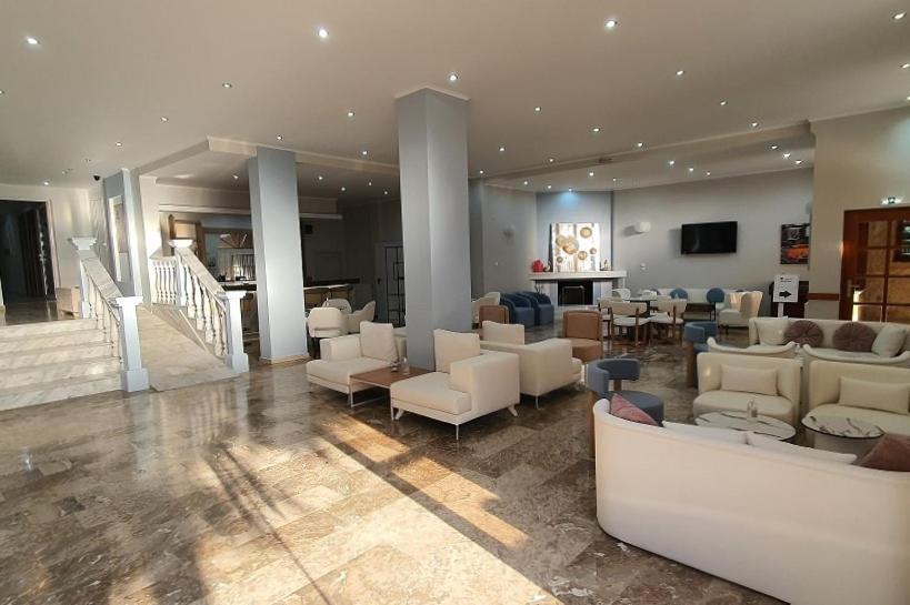 a living room with couches and chairs and a television at ZAKROS HOTEL in Tolo