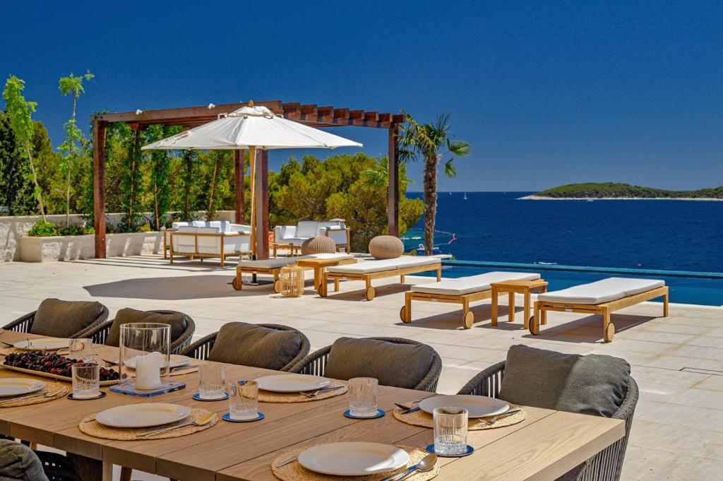 フヴァルにあるLuxury Villa Hvar Deluxe Palace 1 with heated pool, gym and saunaのパティオ(テーブル、椅子、パラソル付)