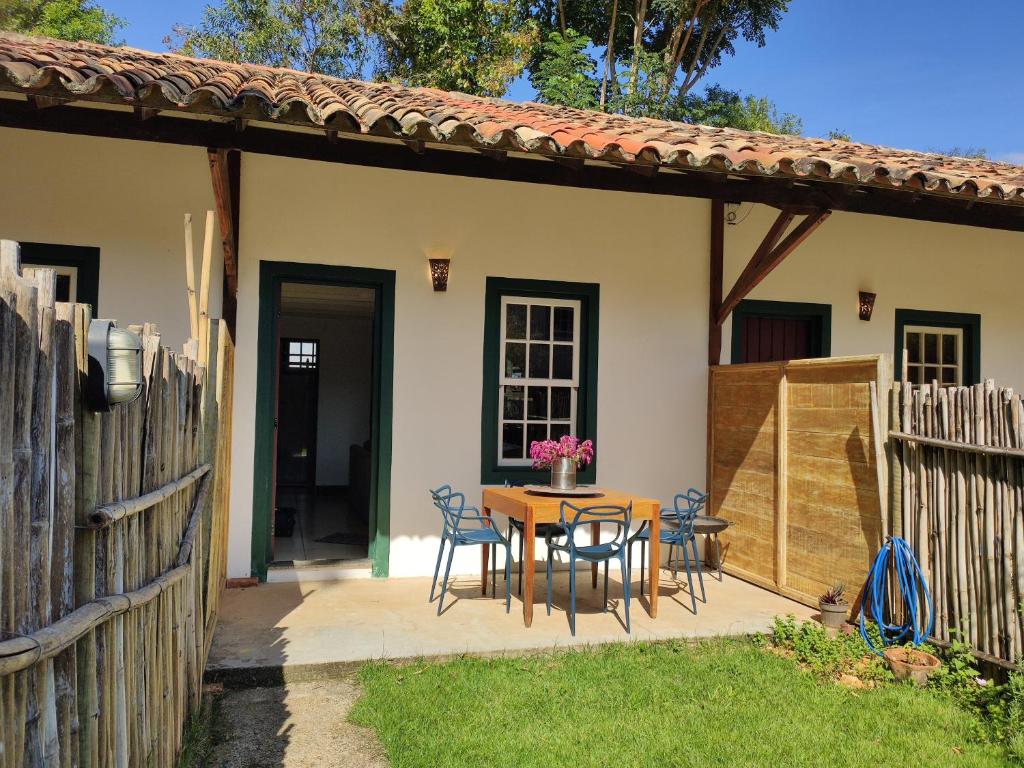 eine Terrasse mit einem Tisch, Stühlen und einem Zaun in der Unterkunft Vila Santana Tiradentes in Tiradentes