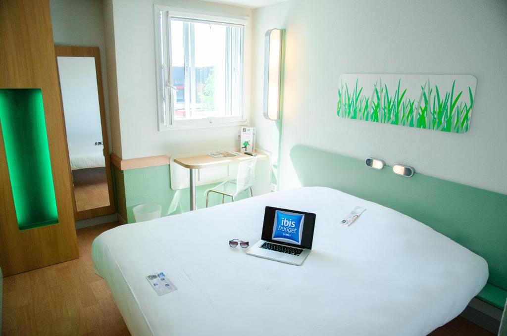a room with a bed with a laptop on it at ibis budget Aeroport le Bourget Garonor in Le Blanc-Mesnil