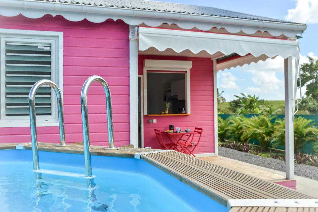 una casa rosa con piscina frente a ella en Les jardins de CHANTILLY -Bungalows 4 étoiles avec jardins et piscines privées en Baie-Mahault