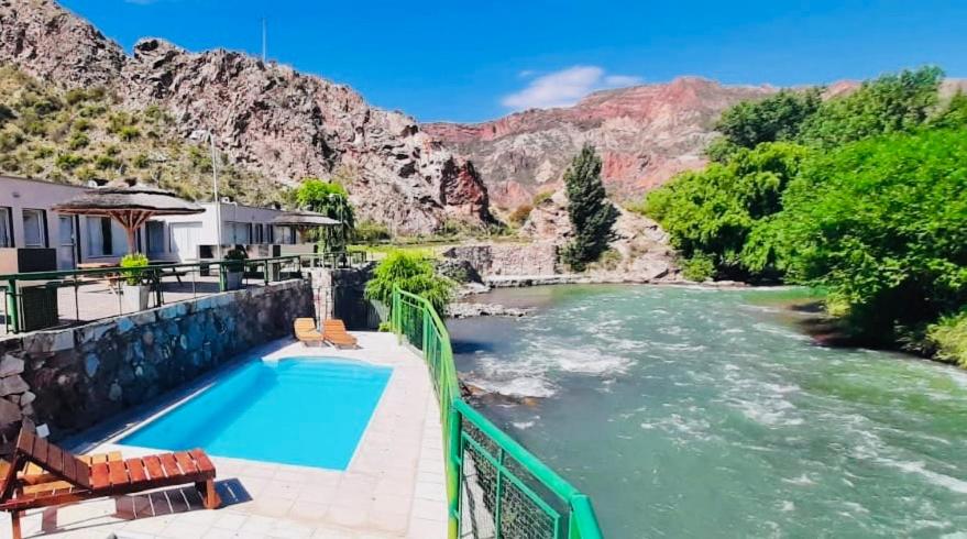 a house with a swimming pool next to a river at Cabañas Cerro Colorado in Valle Grande