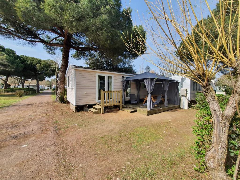 una roulotte bianca con tenda in un cortile di Camping à la Cotinière-Piscine-Bungalow cosy entre Océan et Pinède a La Cotinière