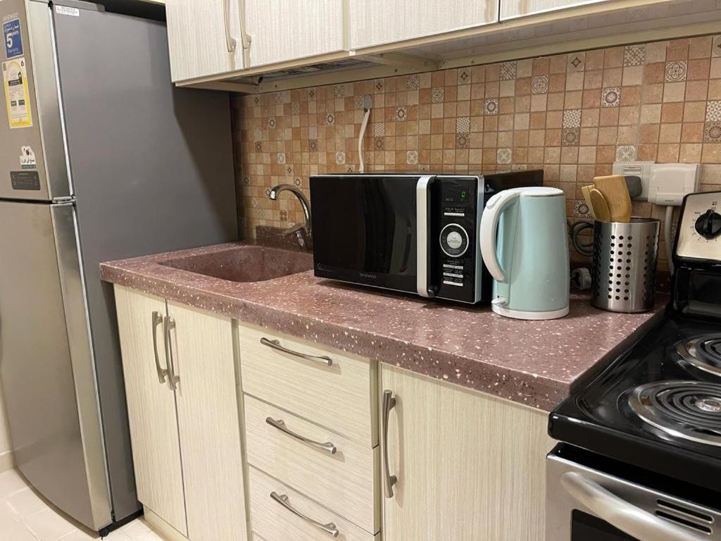 a kitchen counter with a microwave and a refrigerator at Altelal Tower Apartment in Makkah