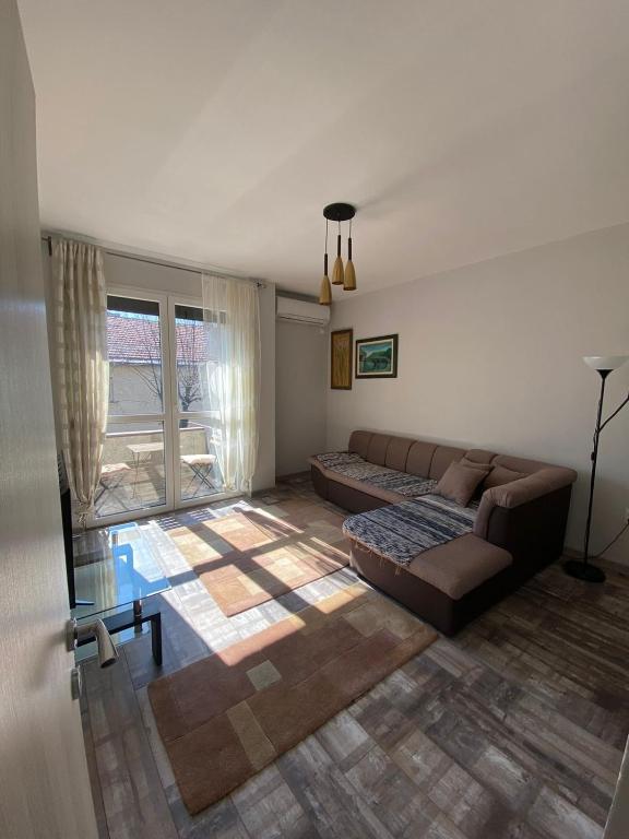 a living room with a couch and a large window at Apartmani Vila in Cetinje