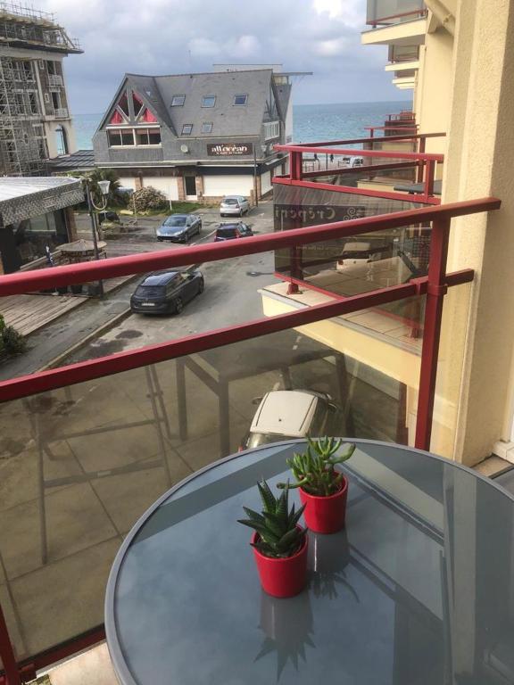 uma mesa de vidro com dois vasos de plantas numa varanda em Appartement Perros-guirec petite terasse vue mer. em Perros-Guirec