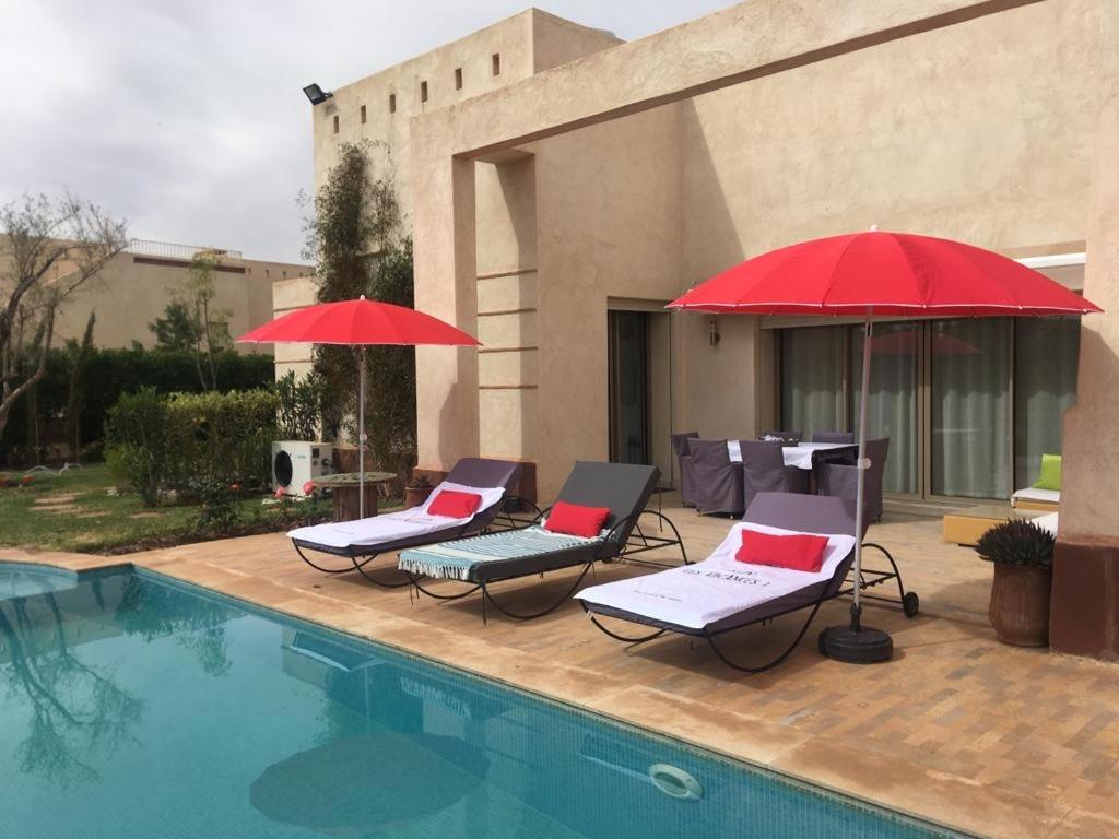 two patio chairs and umbrellas next to a pool at fleur de marrakech in Marrakesh