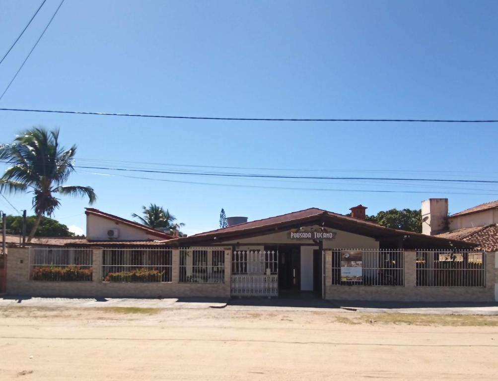 a building with a fence and a palm tree at Pousada Tucano in Prado