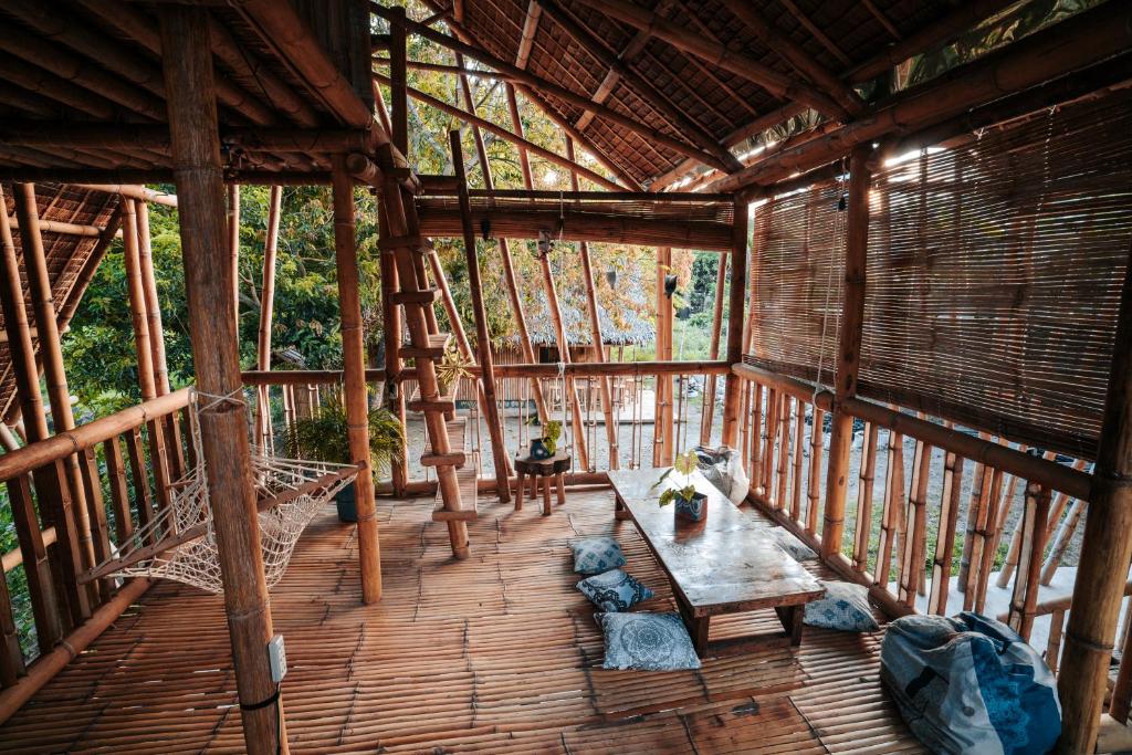 a porch of a wooden cabin with a table and chairs at Mango Tree Eco-Hostel in Dauin