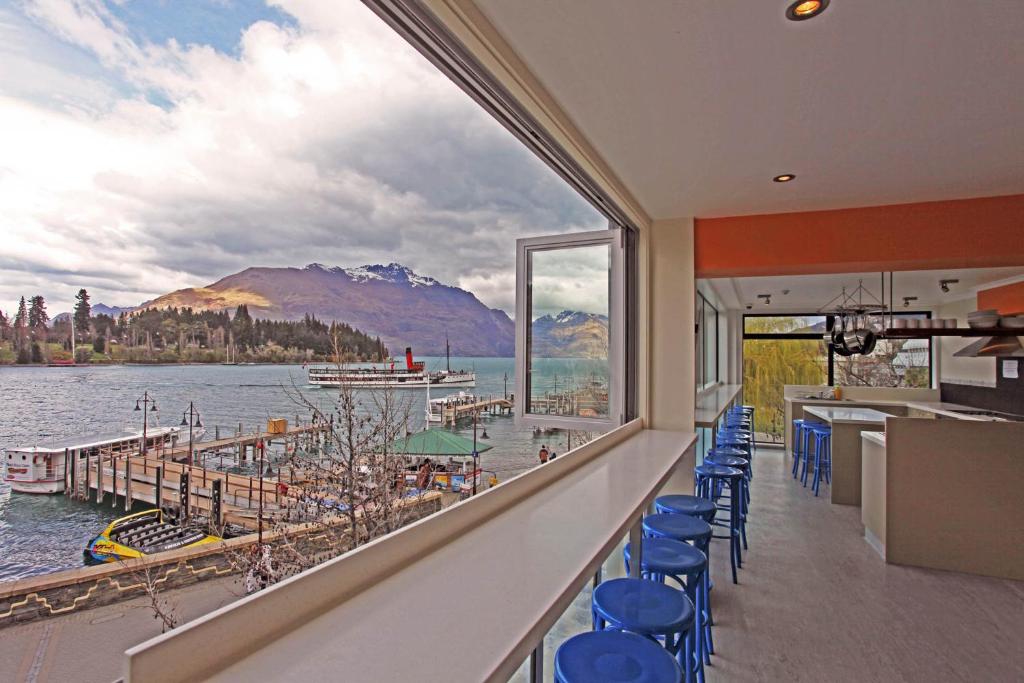 a bar with blue chairs and a view of the water at Absoloot Hostel Queenstown in Queenstown
