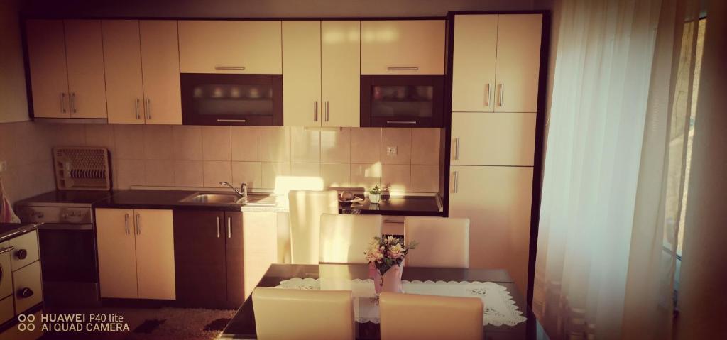 uma cozinha com armários brancos e uma mesa com flores em Apartman Bošnjak Ramsko jezero em Podbor