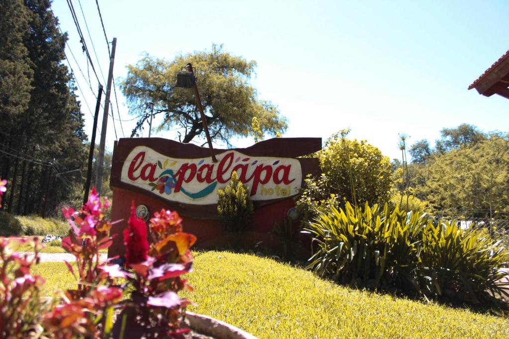 a sign for a laaldo sign in a garden at La Palapa ApartHotel in Villa General Belgrano