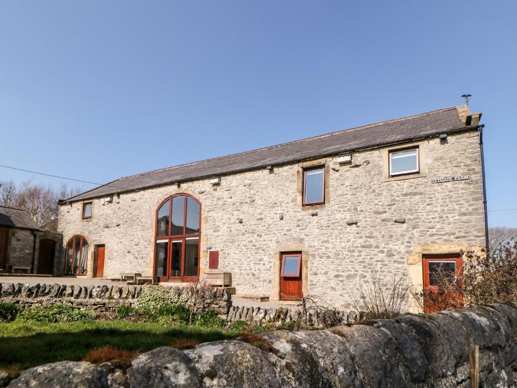 ein altes Steinhaus mit einer Steinmauer in der Unterkunft Broadway Barn in Millers Dale