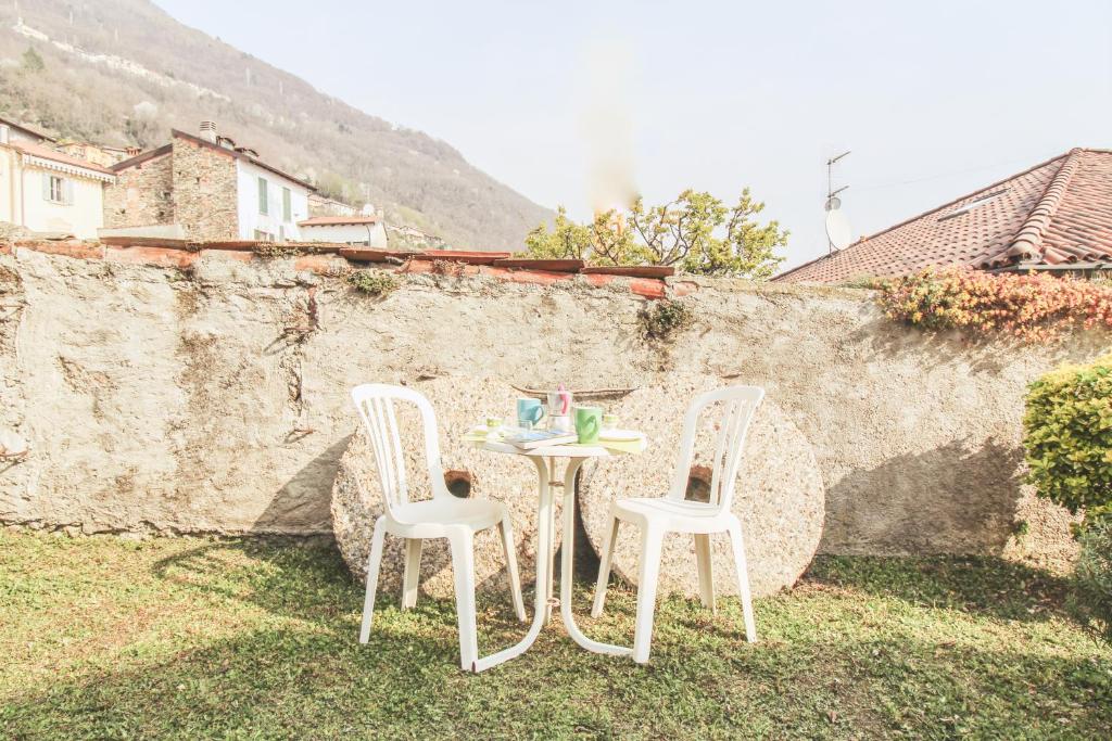 zwei Stühle und ein Tisch im Gras neben einer Wand in der Unterkunft Casetta Pina in San Siro