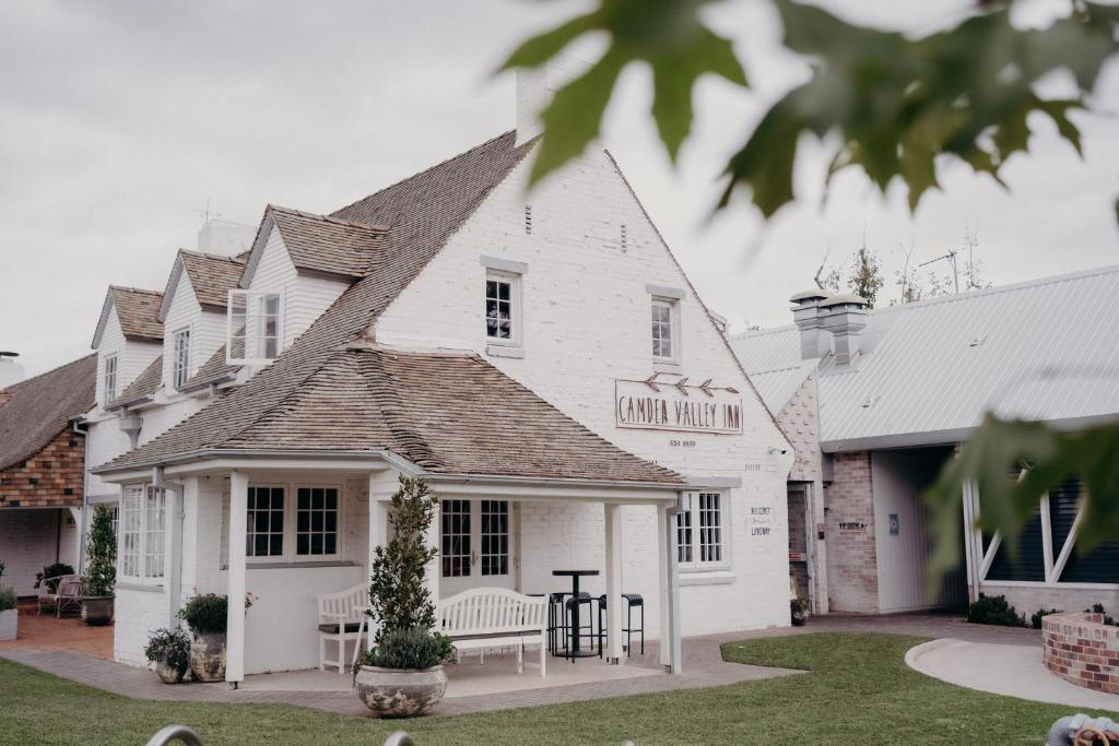 uma casa branca com uma mesa e cadeiras num quintal em Camden Valley Inn em Camden