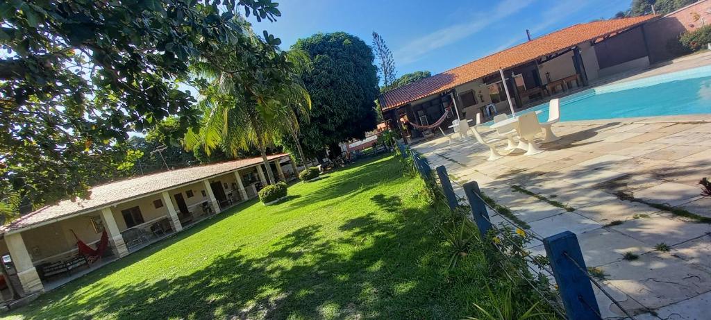 a green yard next to a building with a swimming pool at Hotel Fazenda Recanto das Águias in Aquiraz