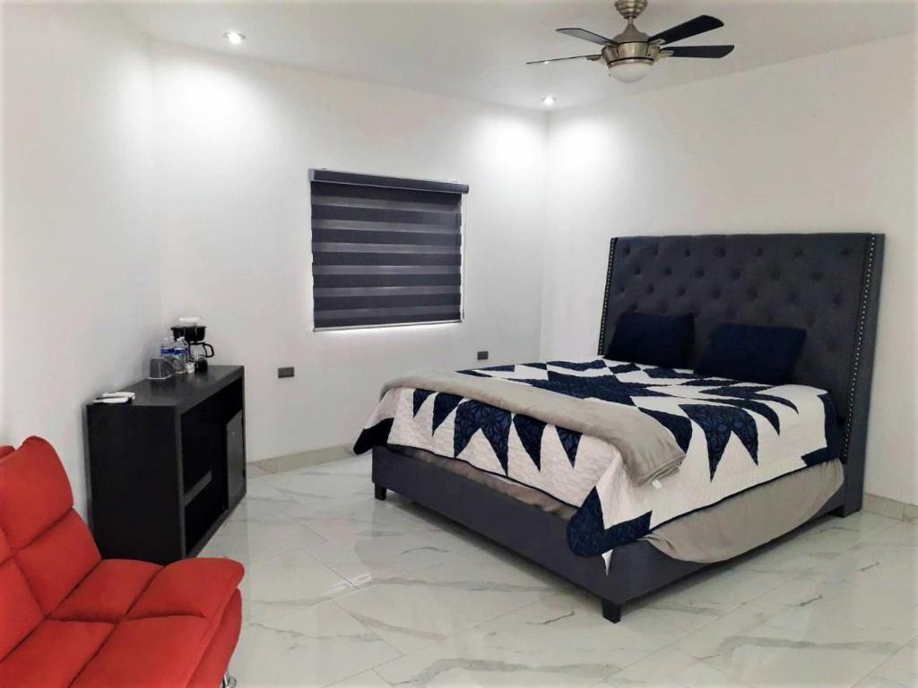 1 dormitorio con 1 cama y 1 silla roja en Santa Fé Apartamentos en Puerto Peñasco