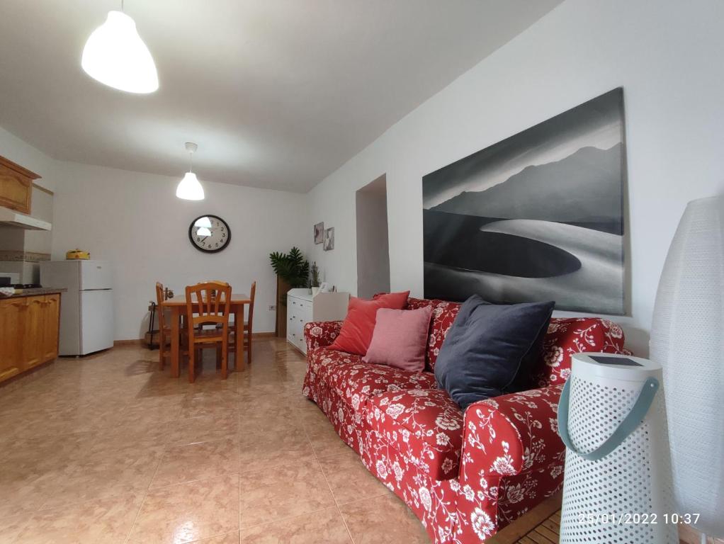 sala de estar con sofá rojo y cocina en Casa Nela. Rural y acogedora en Las Puntas El Hierro en Frontera