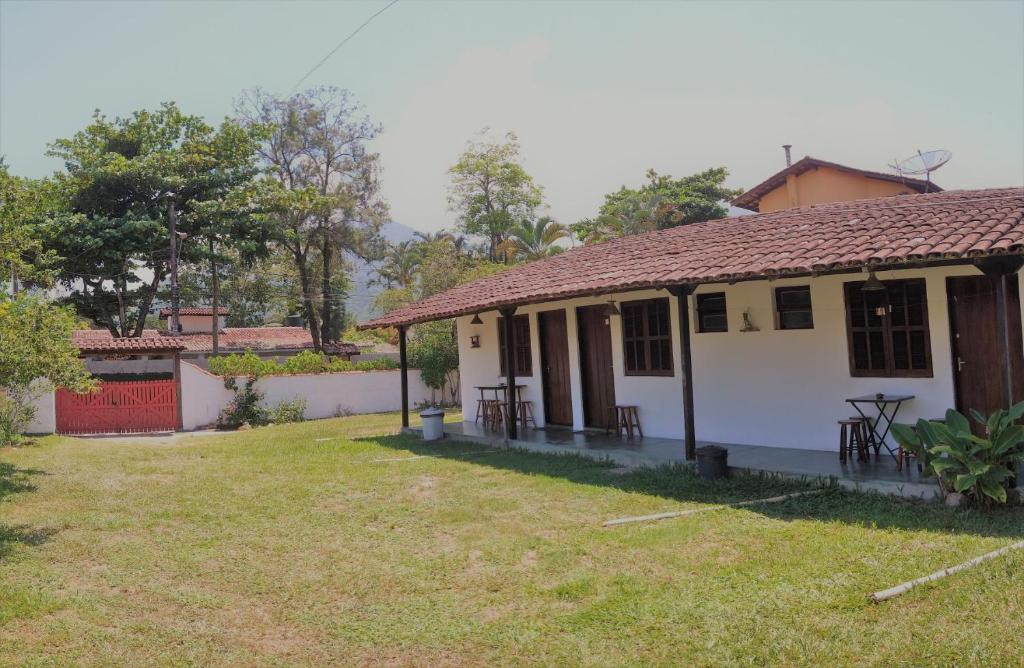 una pequeña casa blanca con un patio de césped en Chalé das Princesas en Ilhabela